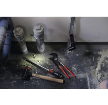 Sanitärinstallation mit Abwasserrohren, Hammer, Schraubendreher und Rohrzange.