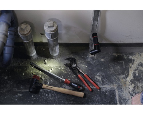 Installation sanitaire avec tuyaux d''évacuation, marteau, tournevis et pince multiprise.