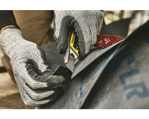 Eine Person schneidet Dachpappe mit einem Stanley Cuttermesser.