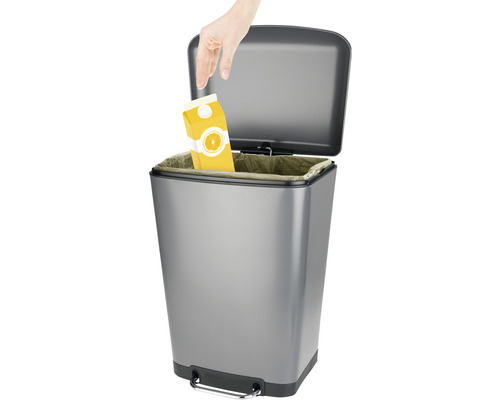 Ein silberfarbener Treteimer wird mit einer Getränkepackung befüllt