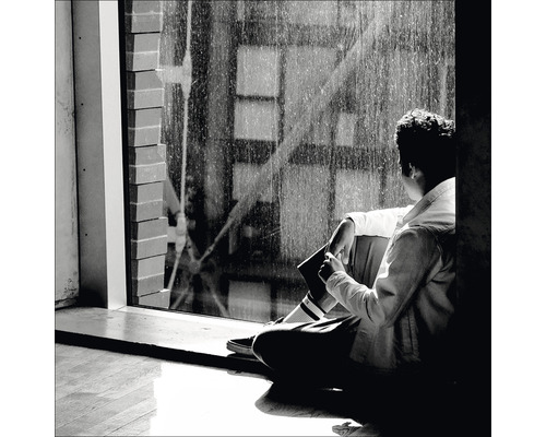 Eine Person sitzt am Fenster und schaut nach draußen.