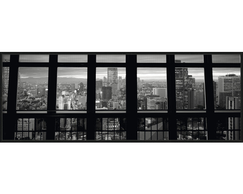 Photographie en noir et blanc avec vue à travers une fenêtre sur une ville