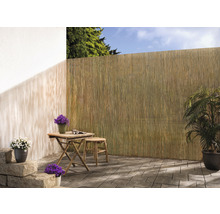 Terrasse avec brise-vue en roseau, table en bois et plantes