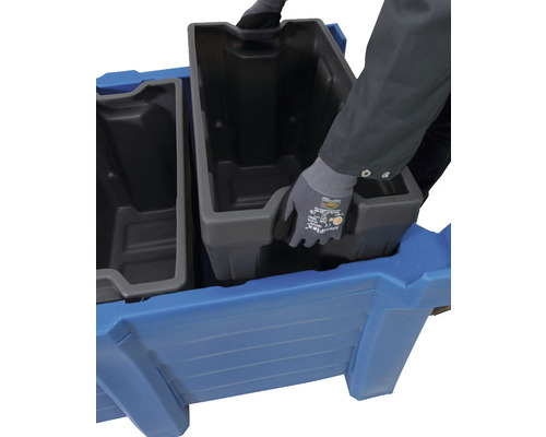 Person setzt Behälter in einen blauen Pflanzkasten