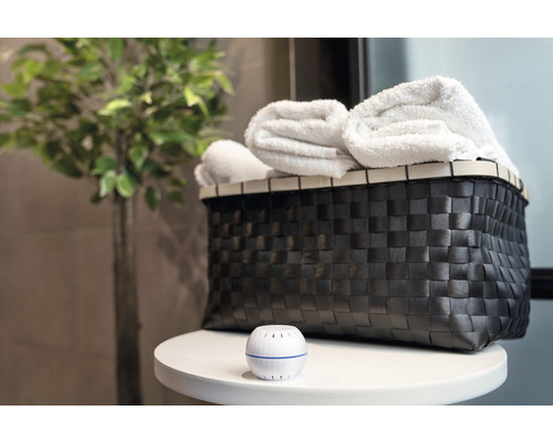 Scène décorative avec panier, serviettes et désodorisant sur une table.