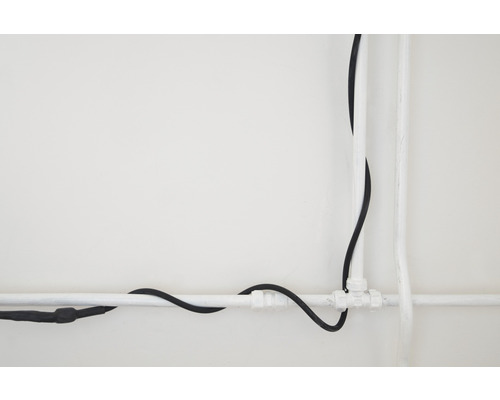 Installation von Elektrokabel und Wasserrohr an einer Wand