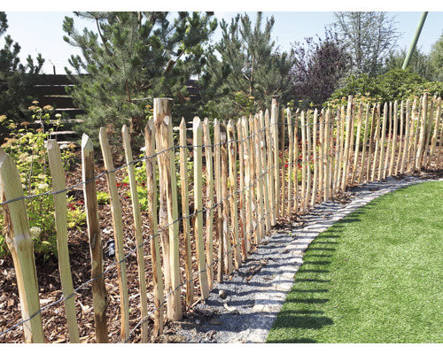 Holzzaun begrenzt einen Gartenbereich mit Rasenfläche.