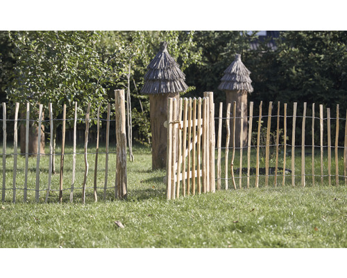 Gartenszene mit offenem Holzzaun und Bienenkörben im Hintergrund