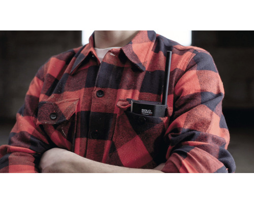 Une personne portant un dispositif de sécurité pour travailleur isolé dans sa poche de chemise.