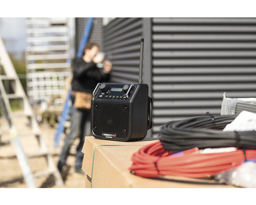 Radio de chantier avec antenne et câbles, avec un ouvrier du bâtiment en arrière-plan