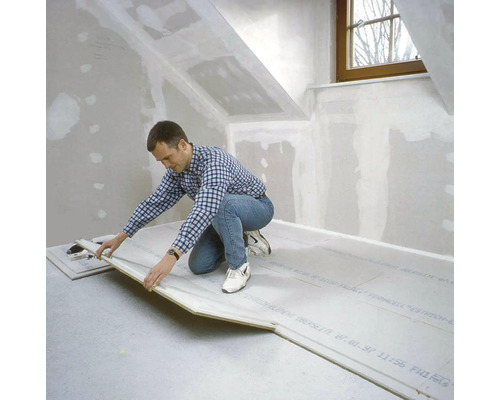 Mann verlegt Trockenestrich in einem Dachgeschossraum