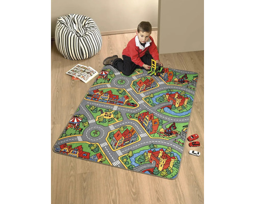 Spielteppich mit Straßenmuster und Kind beim Spielen mit Spielzeugautos und einem Spielzeugbagger