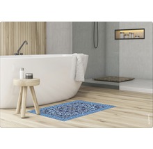 Badezimmer mit freistehender Badewanne, Holzhocker und blauer Teppichfliese mit Ornamentmuster