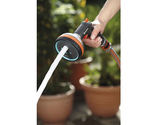 Gartenschlauch Spritzpistole mit Wasserstrahl in der Hand.