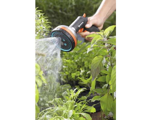 Eine Hand hält einen Gardena Duschkopf und bewässert Pflanzen.