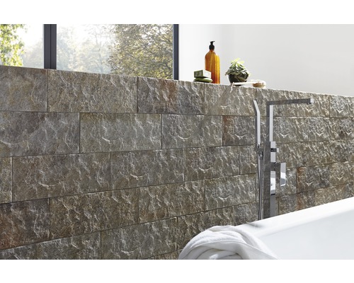 Badezimmergestaltung mit Natursteinwand, Badewanne und Armaturen