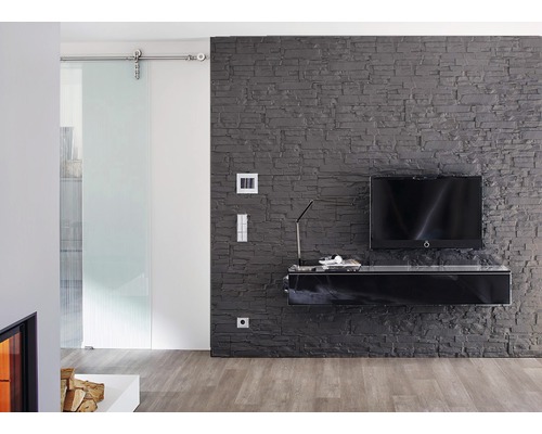 Wohnzimmer mit Schiebetür, grauer Steinwand und schwarzem TV-Möbel