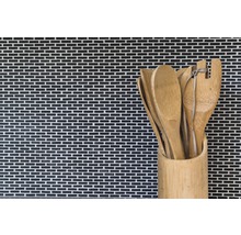 Cuillères en bois et spatules dans un récipient en bambou devant un mur en mosaïque