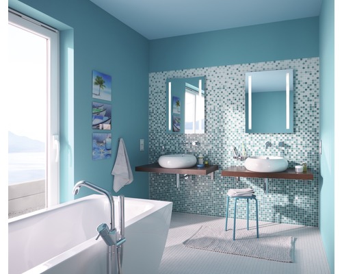 Salle de bains lumineuse avec baignoire, deux lavabos, miroirs éclairés et murs carrelés en mosaïque