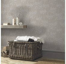 Gemütliches Zimmer mit floral gemusterter Tapete, Weidenkorb und Holzboden