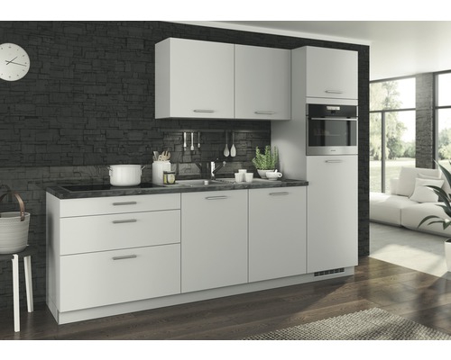 Cuisine intégrée claire avec appareils électriques devant un mur en pierre sombre