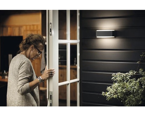 Femme ouvrant la porte d''entrée avec applique murale extérieure