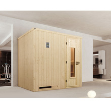 Sauna en bois avec porte vitrée et élément de commande dans une pièce lumineuse.