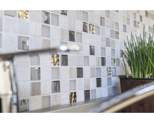 Nahaufnahme einer Wand mit Mosaikfliesen und einer Topfpflanze.