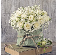 Bouquet de roses blanches et de gypsophile dans un sac en papier vert sur un livre