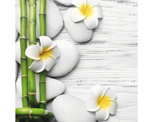Arrangement décoratif avec tiges de bambou, pierres blanches et fleurs de frangipanier sur une table en bois.