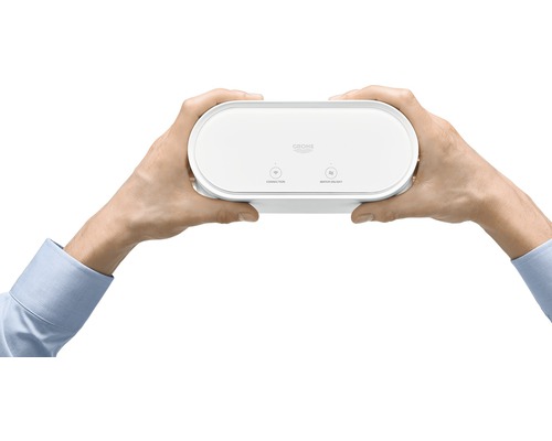 Eine Person hält ein Grohe Sense Guard Wassersicherheitssystem.