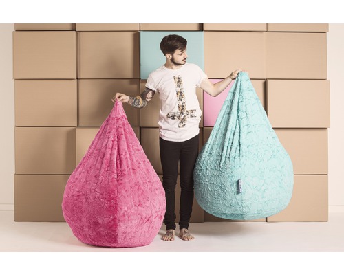 Un homme tient deux poufs en tissu en forme de goutte