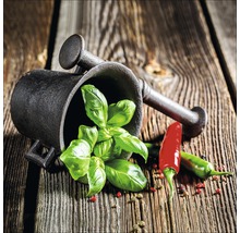 Mörser mit Basilikum und Chili auf Holztisch