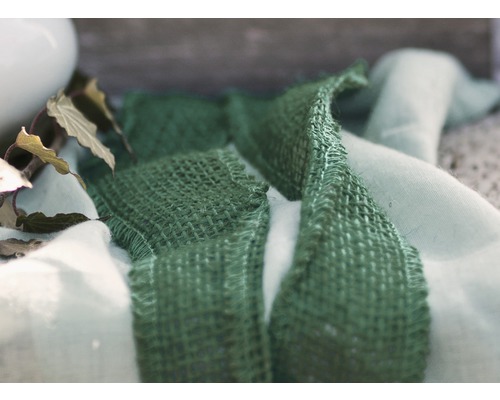 Dekoratives Arrangement mit grünem Textilband und Stoff