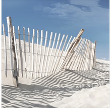 Vue d''une clôture décorative en bois dans le sable sous un ciel bleu