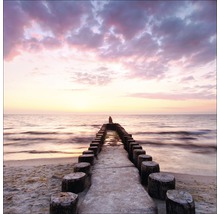 Strand mit Holzpfosten im Meer bei Sonnenuntergang