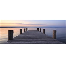 Jetée en bois menant à des eaux calmes au coucher du soleil