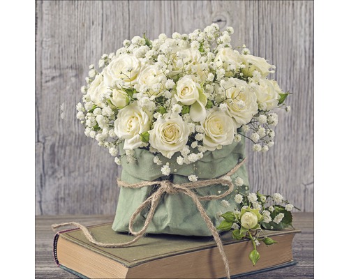 Arrangement de roses et de gypsophile dans un emballage en papier sur un livre