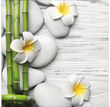 Décoration avec bambou, pierres blanches et fleurs de frangipanier sur fond de bois clair