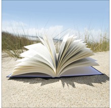 Aufgeschlagenes Buch liegt auf Sand