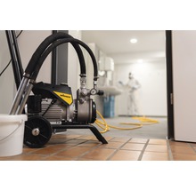 Pulvérisateur de peinture en cours d''utilisation avec une personne portant un équipement de protection en arrière-plan