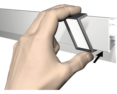 Main fixant un rail métallique à une plinthe murale