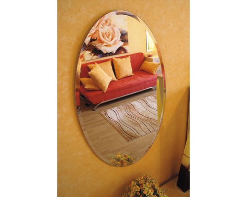 Miroir ovale sur un mur reflétant une pièce avec un canapé et un tapis