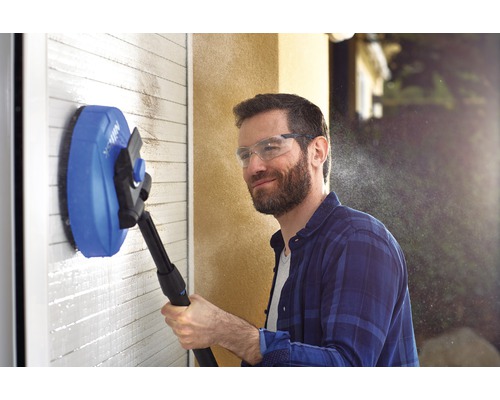 Homme nettoie un mur avec une brosse rotative et un nettoyeur haute pression