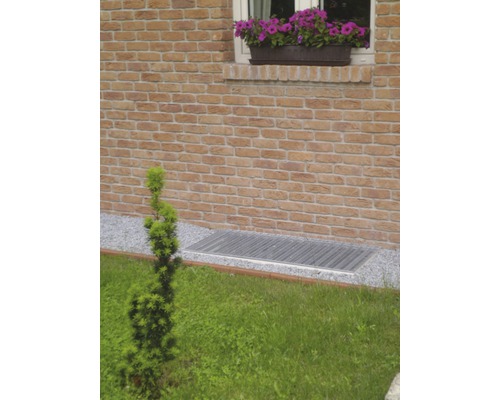 Aussenaufnahme eines Kellerschachts mit Gitterrost und einer Ziegelwand