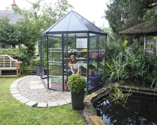 Gewächshaus im Garten mit Teich und Gärtnerin
