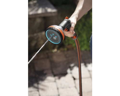 Eine Hand hält eine Gartenspritze, aus der Wasser austritt.