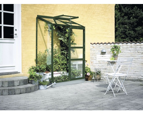 Anlehngewächshaus Halls Altan 2 Blankglas 3 mm 132x69 cm grün Wandgewächshaus mit Pflanzen neben Hauswand und Sitzgruppe