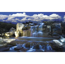 Künstlicher Wasserfall mit Felsen und Pflanzen unter blauem Himmel
