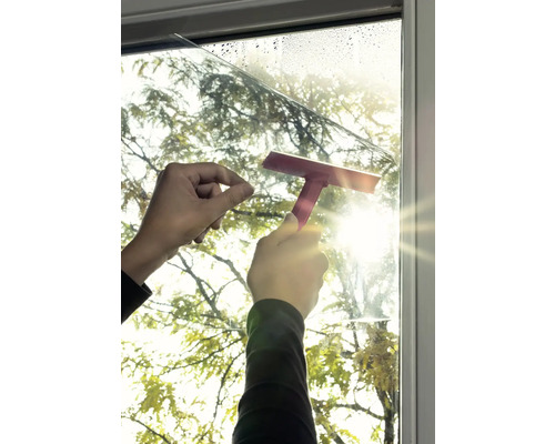Photo extérieure d''une personne appliquant un film pour fenêtre avec une raclette
